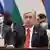 Tokayev, in a dark suit and red tie, sits behind a desk at a summit meeting