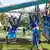 School children play on pullup rings and a rope bridge in a playground 