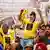 Protestierende in gelben T-Shirts in Neu Delhi. Ein Mann trägt die Maske des Politikers Arvind Kejrival