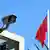 Eine Kamera am Zaun des Chinesischen Generalkonsulats. Im Hintergrund weht eine chinesische Flagge.